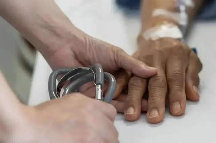 nurse holding elderly man's hand