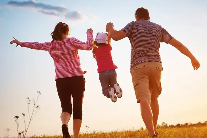 family holding up child at sunset