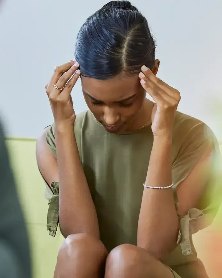 a woman sitting on a couch with her head in her hands