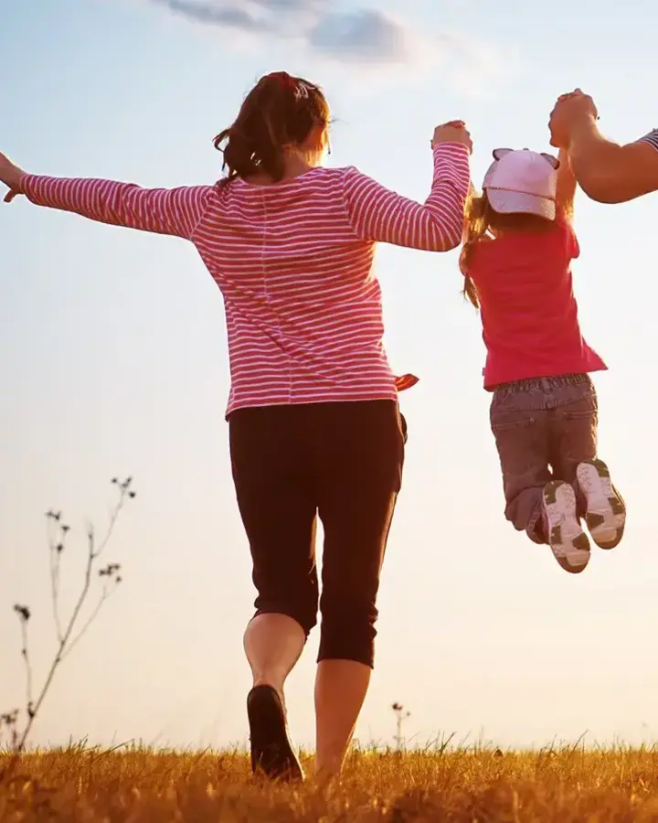 a couple running through a field at sunset