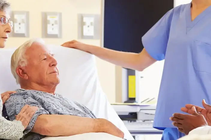 nurse talking to elderly patient in bed