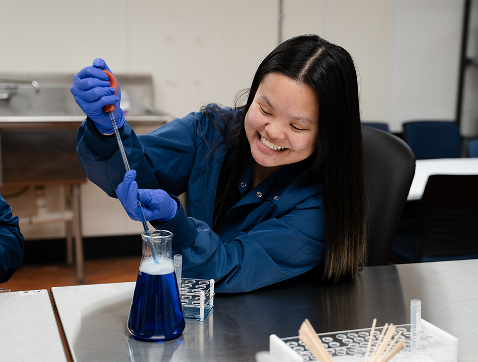 A-woman-in-scrubs-holding-putting-liquid-in-a-beaker